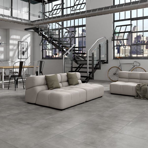 Heller Wohnbereich im Loft-Stil mit grauen Bodenfliesen in Betonoptik, modularen Sofas und Fenstern im Industriedesign.