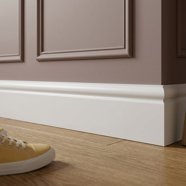 Weiße Sockelleiste montiert an einer Wand mit Wandpaneelen über einem Holzboden.