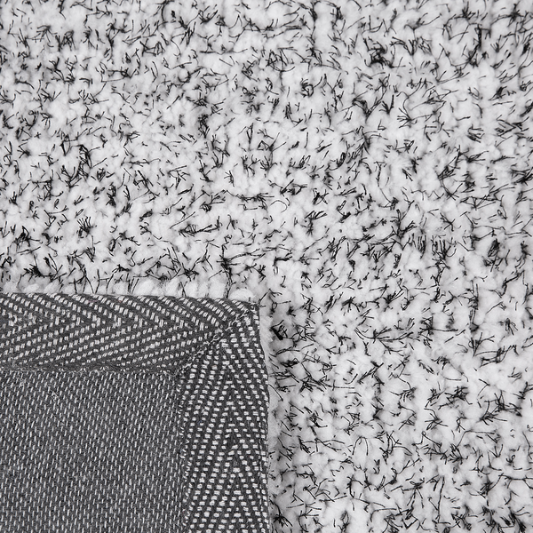 Nahaufnahme eines Hochflor-Teppichs mit einer umgeknickten Ecke und einer strukturierten Rückseite.