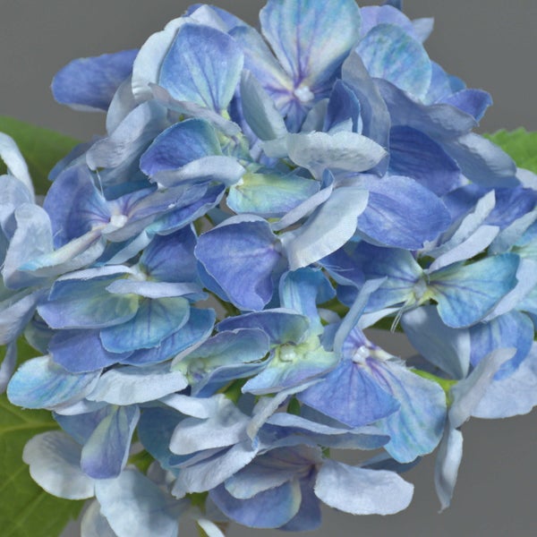 Künstliche Hortensie mit blauem Blütenkopf und grünem Stiel mit zwei Blättern.