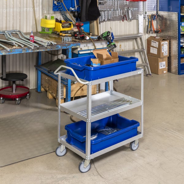 Werkstattwagen mit drei Ablagen und Werkzeugen in einer Werkstatt.