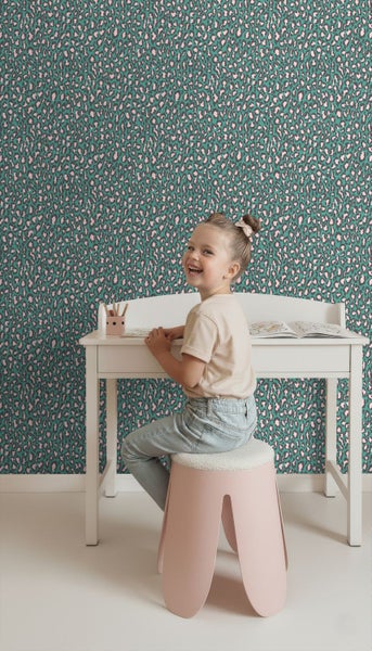 Vliestapete mit Leopardenmuster in einem hellen Kinderzimmer mit weißem Schreibtisch und rosa Hocker.