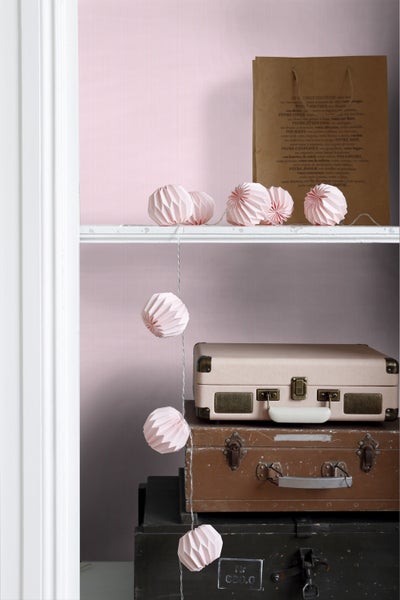 Dekorative Szene mit Papiergirlande, Gepäck und Papiertüte auf einem Regal