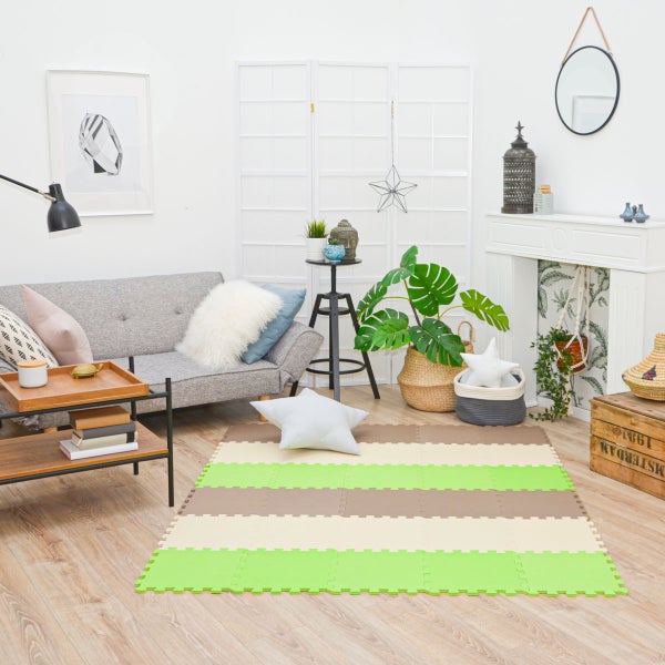 Gestreifte Puzzlematte aus Schaumstoff in einem hellen Wohnzimmer mit Sofa, Pflanzen und Dekoration.