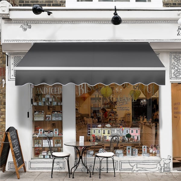 Fassadenansicht eines Ladens mit Markise, Tisch und Stühlen vor dem Schaufenster.