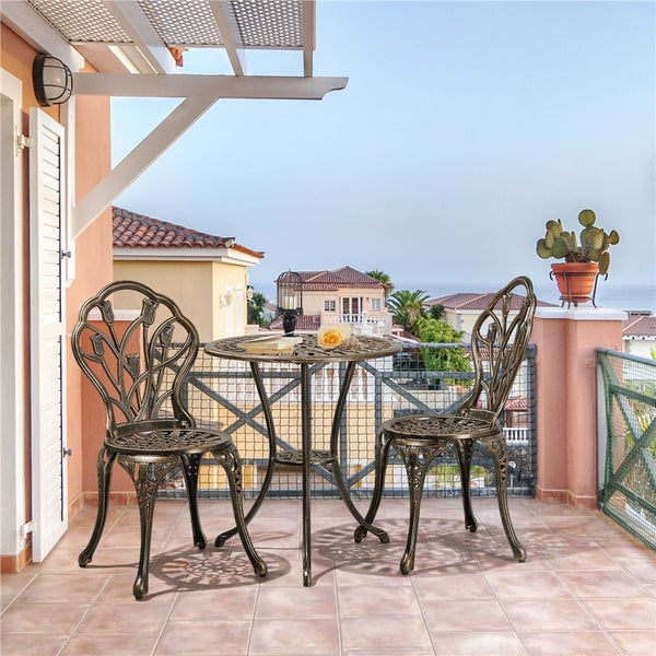 Helles Bistro-Set aus Aluminiumguss mit zwei Stühlen und rundem Tisch, verziertes Tulpen-Design, im antiken Stil auf einem Balkon.