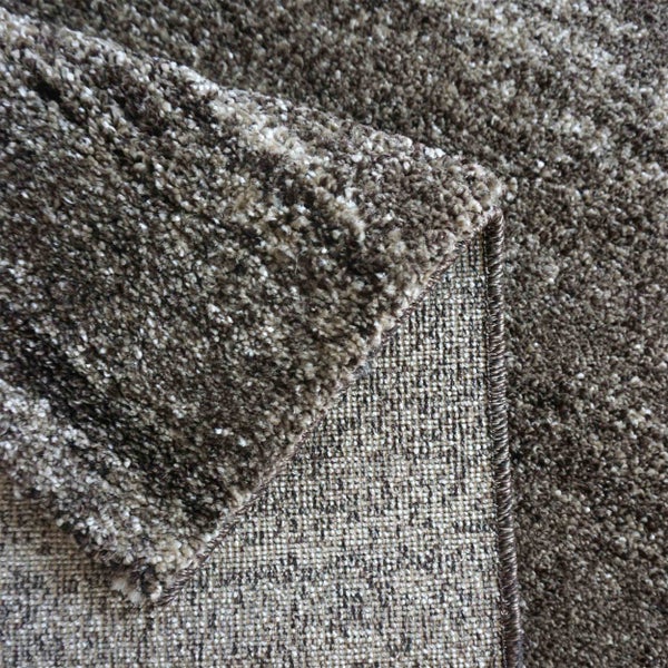 Nahaufnahme eines braunen Shaggy-Teppichs mit Detailansicht der Textur, der Unterseite und der gekettelten Kante.