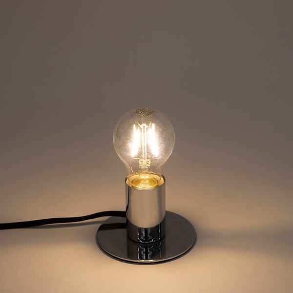 Tischleuchte mit glänzendem Chrom-Sockel und eingeschalteter LED-Filament-Glühbirne.