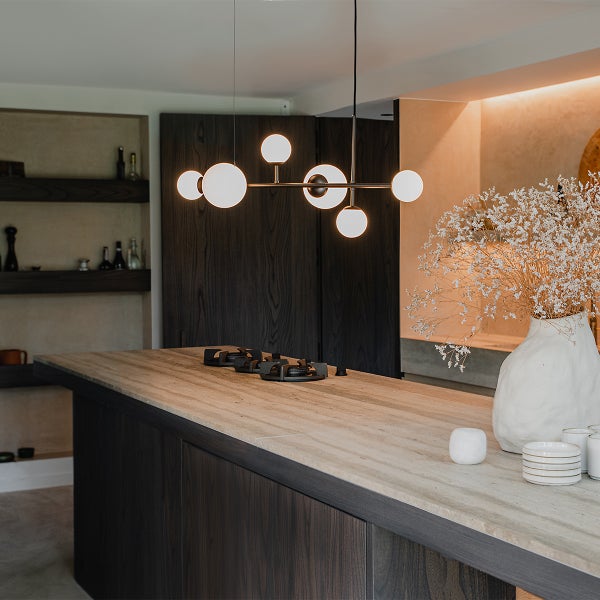 Kücheninterieur mit Kochinsel, Lampe, Kochfeld und Dekor