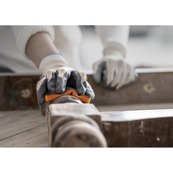Eine Person schleift Holz mit einem Schleifschwamm und Handschuhen