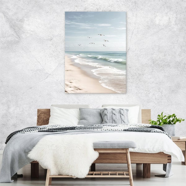 Wandbild mit Strandmotiv über einem Holzbett in einem hell eingerichteten Schlafzimmer mit grauer strukturierter Wand.