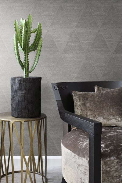 Dekoratives Wohnambiente mit Kaktus im Topf auf Beistelltisch neben Sessel und gemusterter Tapete