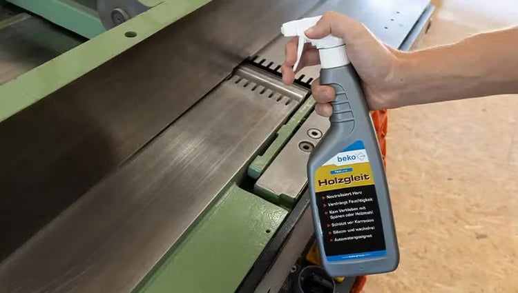 Person verwendet beko Holzgleit Sprühflasche an einer Hobelmaschine zur Pflege der Metalloberfläche.