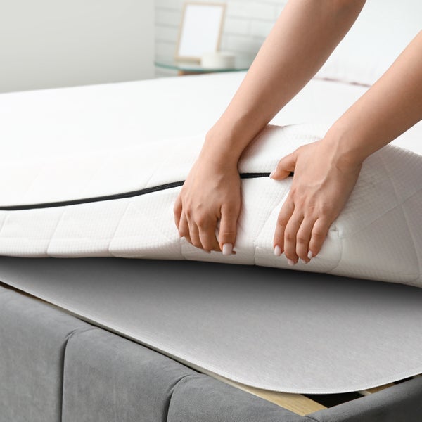 Nahaufnahme einer Person, die eine Matratze auf einem Bett platziert