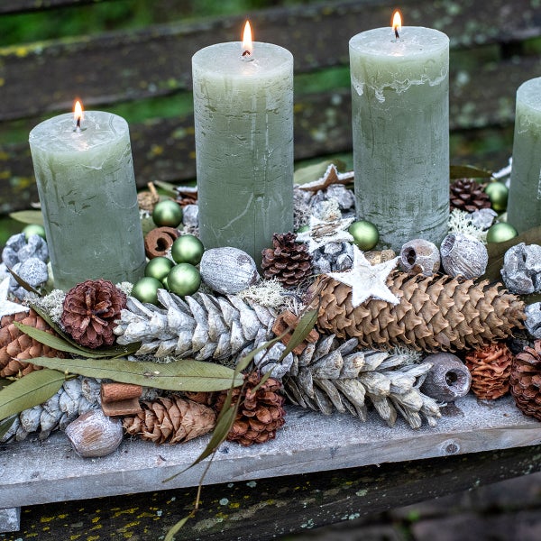 Adventskranz mit vier brennenden Kerzen, Tannenzapfen und Kugeln