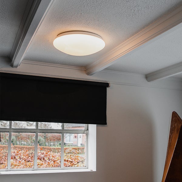 Deckenleuchte in einem hellen Raum mit Rolladen vor dem Fenster.