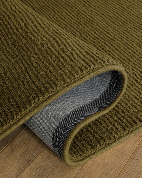 Grüner Teppich mit Rippenstruktur auf einem Holzboden.