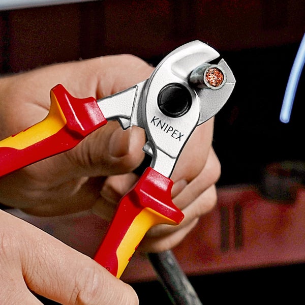 Knipex Kabelschneider beim Schneiden eines Kupferkabels, mit isolierten Griffen in Rot und Gelb.