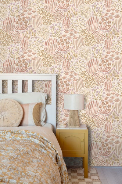 Tapete mit stilisiertem Blumen- und Grasmuster in einem hellen Schlafzimmer mit weißem Holzbett und gelbem Nachttisch.
