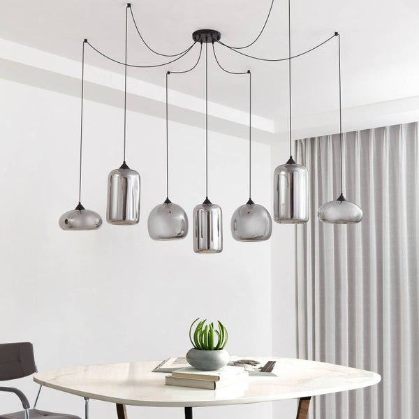 Moderne siebenflammige Pendelleuchte mit rauchfarbenen Glasschirmen in verschiedenen Formen über einem weißen Esstisch.