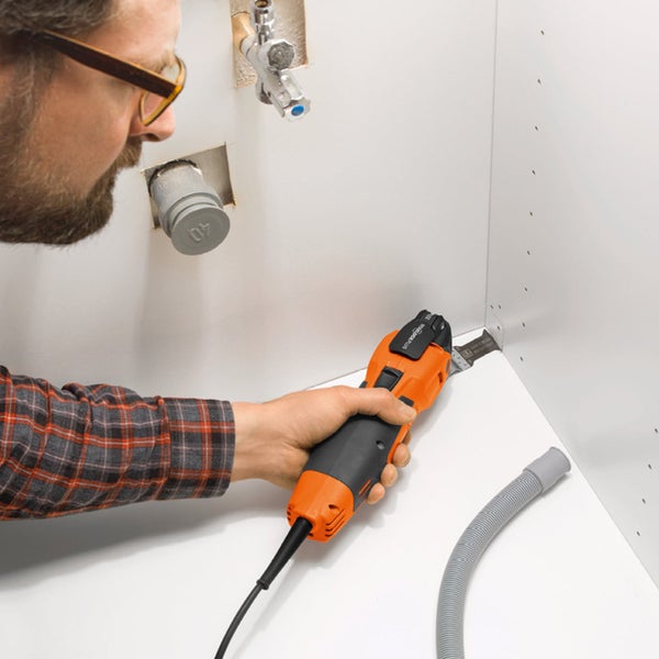 Handwerker benutzt Multifunktionswerkzeug zum Schneiden in einer Ecke