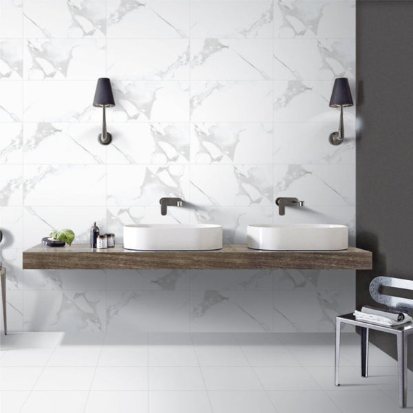 Helles Badezimmer mit weißen Marmorfliesen an Wand und Boden, Waschtisch mit zwei Waschbecken und Wandlampen