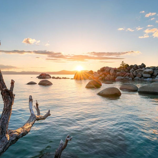 Landschaft mit See, Felsen und Sonnenaufgang