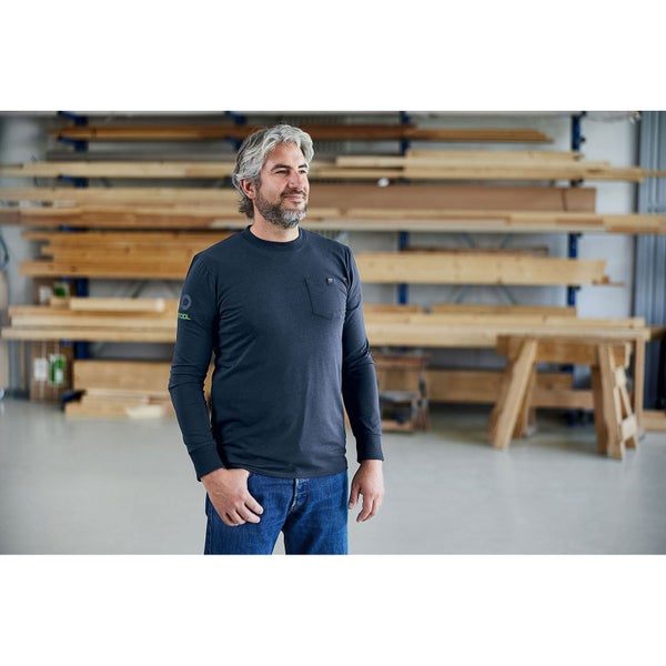 Mann trägt ein Langarmshirt in einer Werkstatt mit Holz im Hintergrund