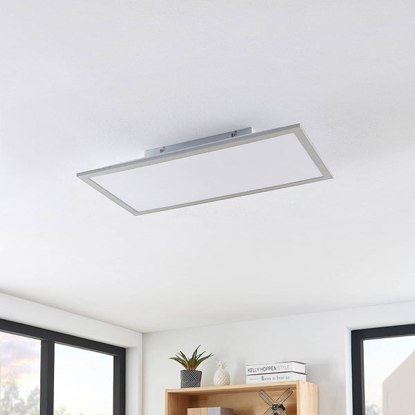 Modernes, rechteckiges LED-Panel mit silbernem Rahmen an einer weißen Decke in einem hellen Raum über einem Holzregal montiert.