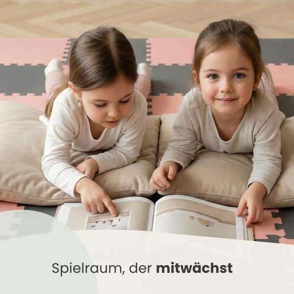 Zwei Kinder liegen auf einer Schaumstoff-Spielmatte und schauen sich ein Buch an, in einem hellen und organisierten Spielzimmer.