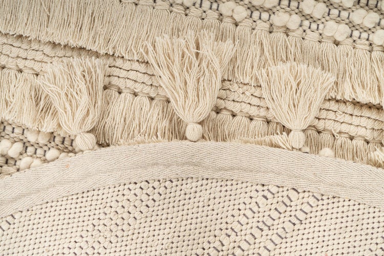 Detailaufnahme eines gewebten Teppichs mit Quasten und Fransen.