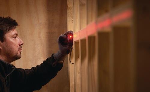 Ein Mann benutzt einen Laser, um ein Holzprojekt auszurichten.