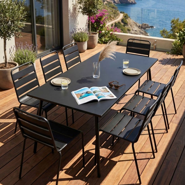 Modernes Gartenmöbel-Set auf einer Holzterrasse mit Meerblick, bestehend aus einem rechteckigen schwarzen Metalltisch und sechs Lamellenstühlen.