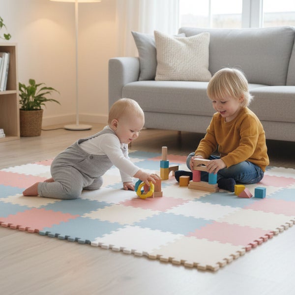 Zwei Kinder spielen mit Holzbausteinen auf einer bunten Schaumstoff-Puzzlematte in einem hellen Wohnzimmer.