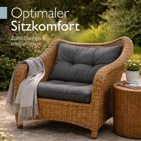 Garten-Loungesessel aus Polyrattan mit grauen Polsterkissen, einer hellen Decke und einem passenden Beistelltisch auf einer Terrasse.