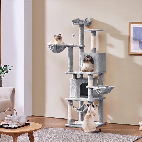 Grauer Katzenbaum mit mehreren Ebenen, Kratzstämmen, Liegekörbchen und drei Katzen in einem Wohnzimmer.