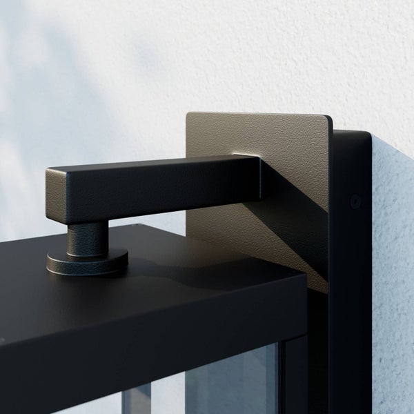 Detail der Wandhalterung und des Arms einer schwarzen Außenwandleuchte aus strukturiertem Metall.