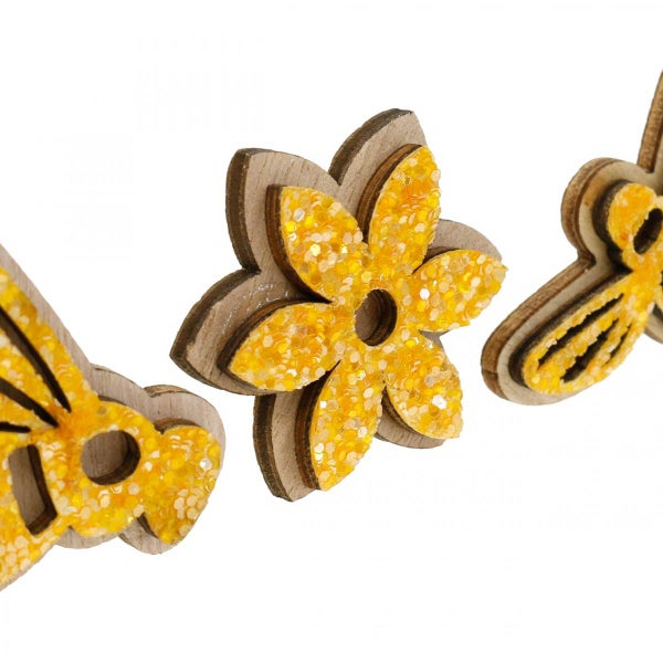 Dekorative Holzfiguren mit glitzernden Akzenten in Blumen- und Bienenmotiven.