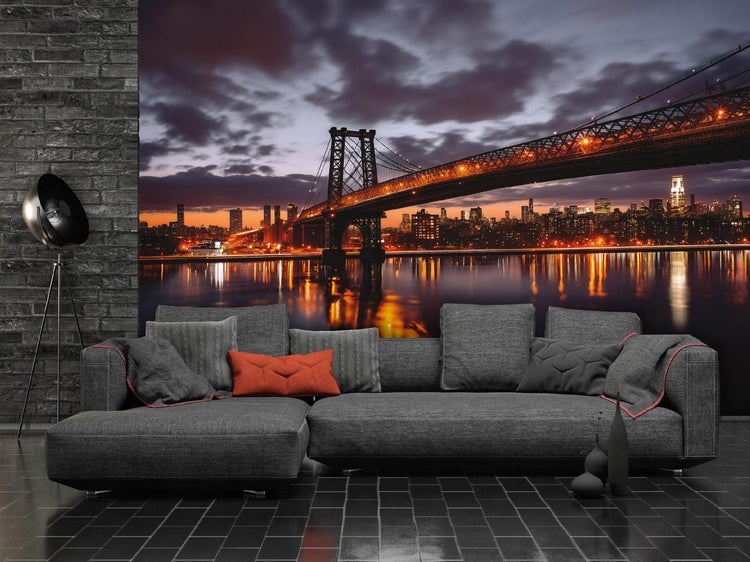 Wohnzimmer mit grauer Couch vor Fototapete mit Stadtansicht bei Nacht.