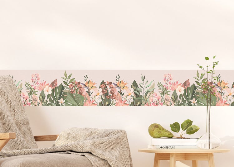 Tapetenbordüre mit tropischem Blumen- und Blättermuster in einem hellen Wohnzimmer mit Sessel und Beistelltisch.