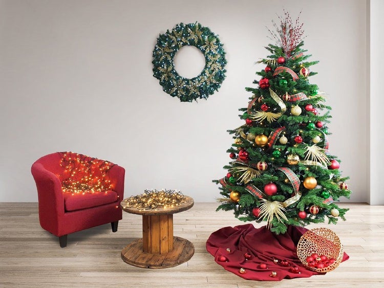 Festlich dekorierter Weihnachtsbaum mit Kugeln und Lichterkette, dazu ein Adventskranz, ein Sessel mit Lichterkette und ein Holztisch.