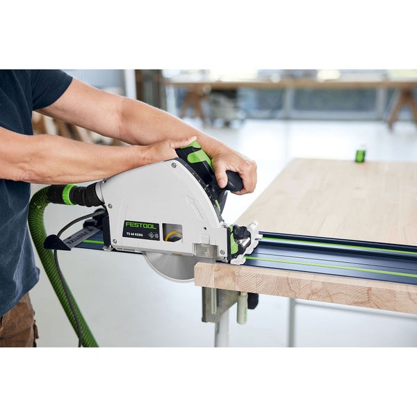 Eine Person schneidet eine Holzplatte mit der Festool Tauchsäge TS 60 KEBQ auf einer Führungsschiene in einer Werkstatt.