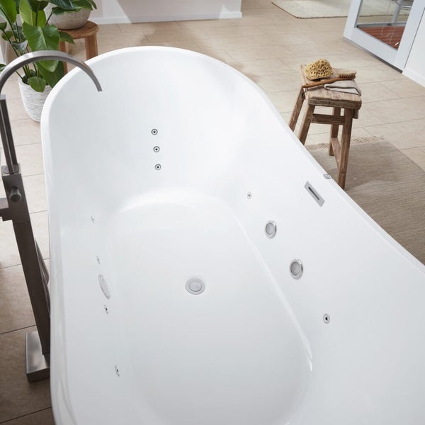 Freistehende Whirlpool Badewanne in einem hellen Badezimmer mit einer freistehenden Armatur und Holzaccessoires.