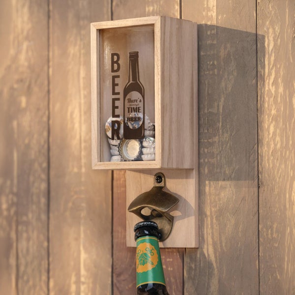 Wand-Flaschenöffner aus Holz mit Metallöffner und Kronkorkensammler aus Glas, montiert an einer Holzwand während eine Bierflasche geöffnet wird.