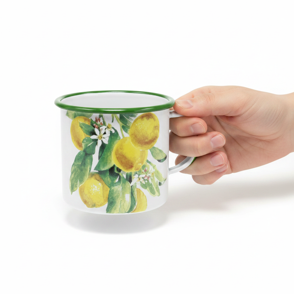 Emaille-Becher mit Zitronenmotiv und grünem Rand, von einer Hand am Henkel gehalten.