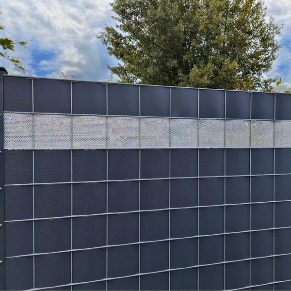 Sichtschutzzaun mit Metalleinsatz und Gitterstruktur vor Baum