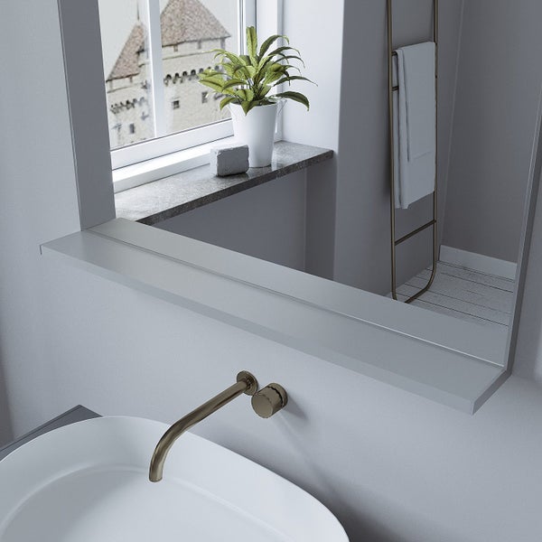 Modernes Badezimmer mit Waschtisch, Wandarmatur in Metalloptik und großem Spiegel mit Ablage vor einem Fenster mit Pflanzen und Handtuchleiter.