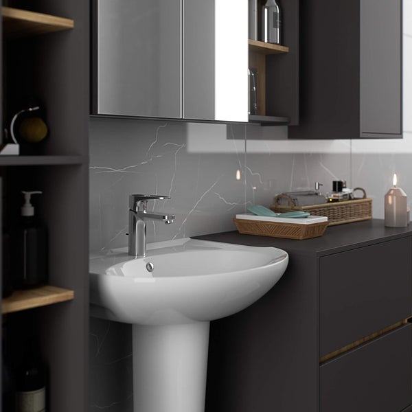 Badezimmerwaschtisch mit Unterschrank, Spiegelschrank und Regalen für Badezimmerutensilien.