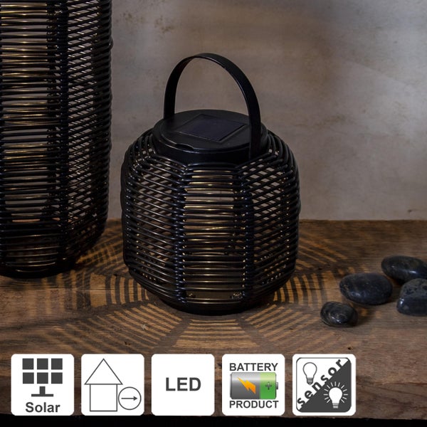 Dekorative Szene mit zwei schwarzen Windlichtern aus Rattan auf einem Holztisch