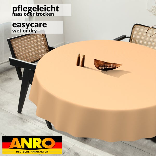 Runde, pflegeleichte Tischdecke auf einem runden Tisch in einem hellen Esszimmer mit Wiener-Geflecht-Stühlen. ANRO Deutsche Manufaktur Logo.